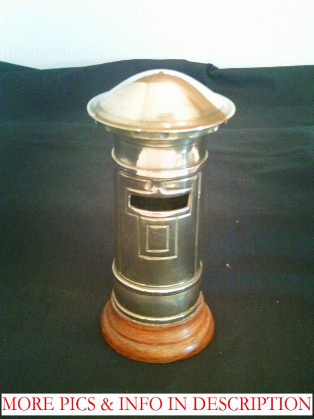 brass moneybox in the shape of an English post box. Sits on a wooden 